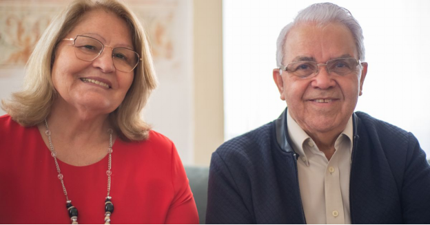An elderly couple sitting together and smiling indoors